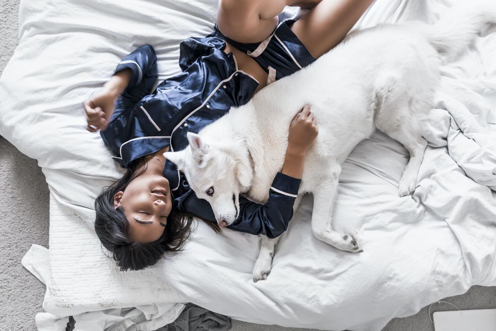woman lying in bed with dog